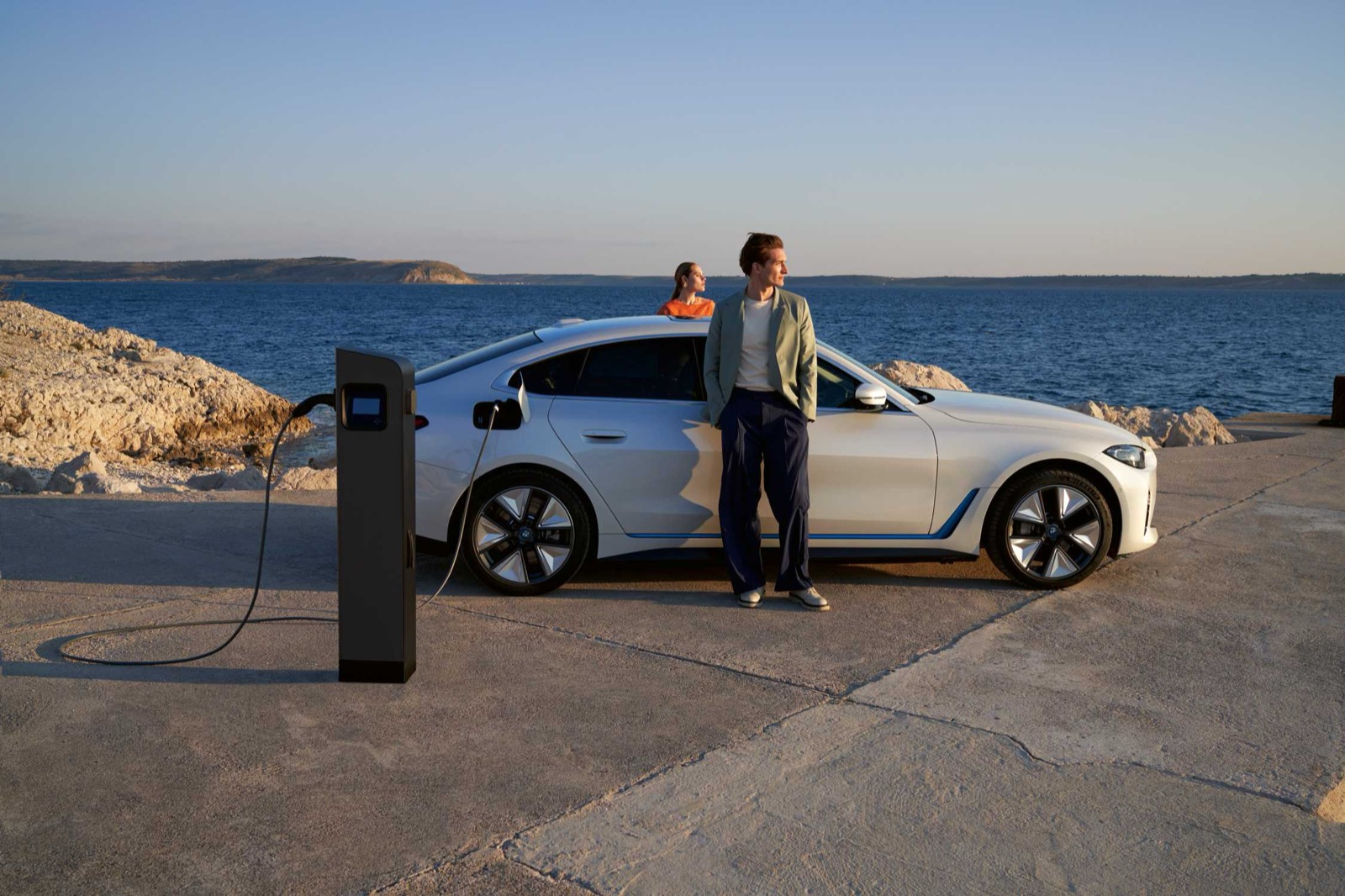 White BMW i4 connected to an outdoor charging station