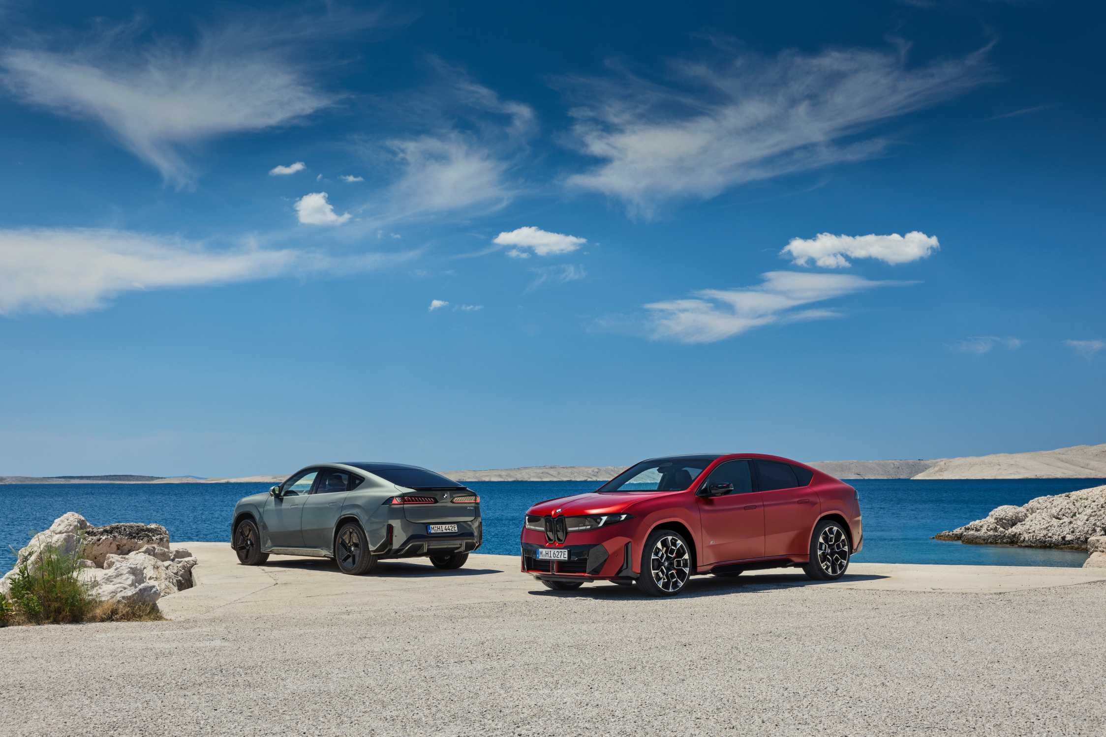 Two BMW iX4 vehicles shown from the front and rear beside the sea